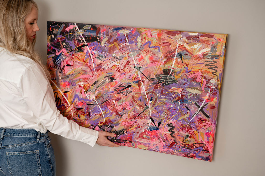 Kiri holding an abstract painting in pinks and purples